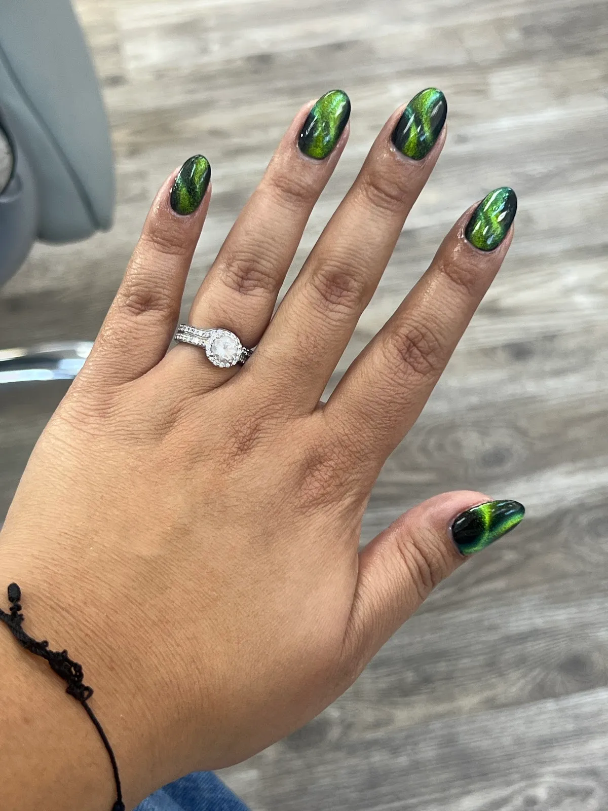 Glossy green cat-eye chrome nails on an almond shape