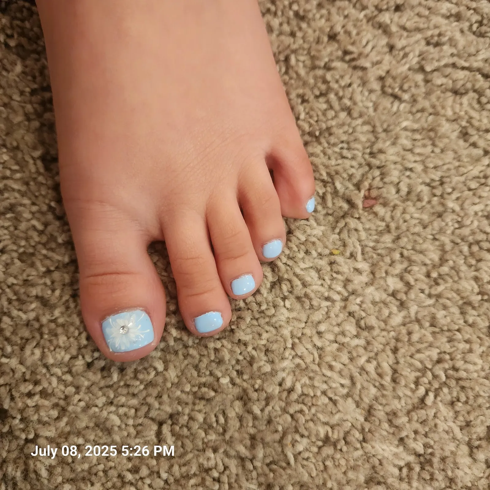 Light blue pedicure with a small white flower painted on the big toe